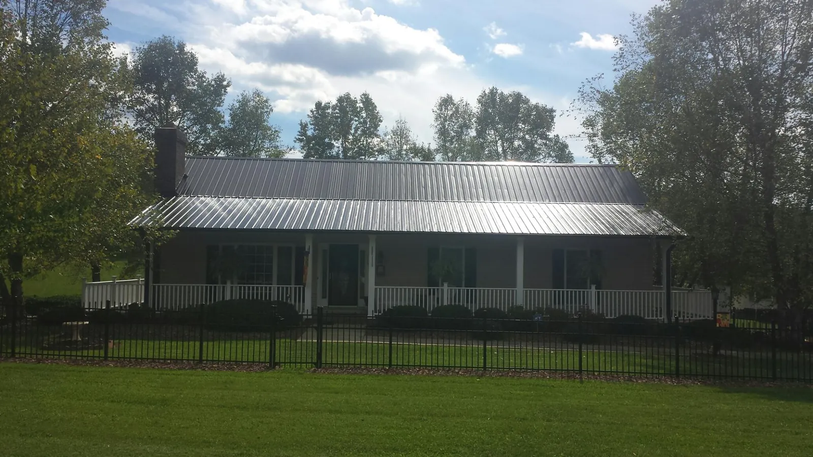 Gray metal roof on a brick ranch with a full width front porch — Gutter Guard Installation work by our crew in Modena